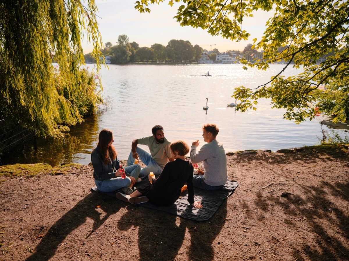 Vier Personen sitzen als Gruppe am Wasser
